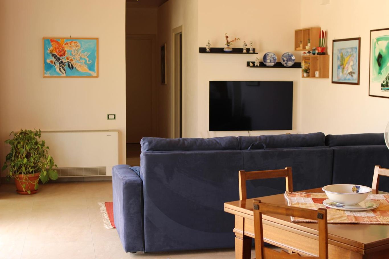 Il living con il divano, la TV, il tavolo da pranzo e le sedie di legno.