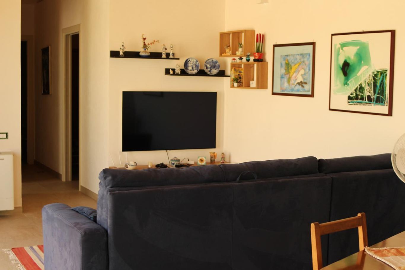 Il living con il divano, la smart TV e i quadri alla parete.