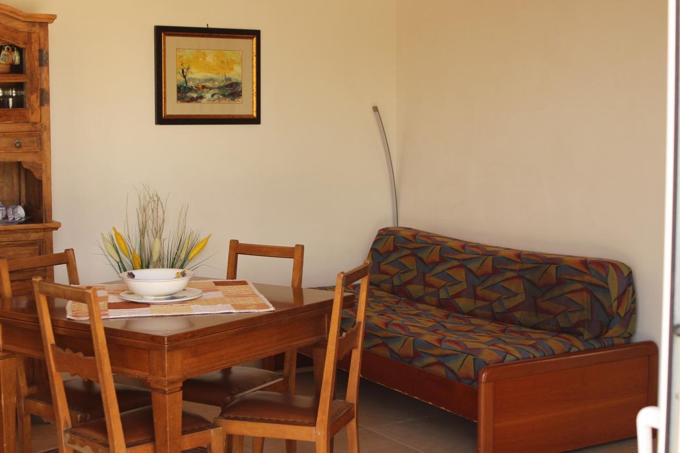 Il tavolo da pranzo con la credenza e il divano letto singolo.