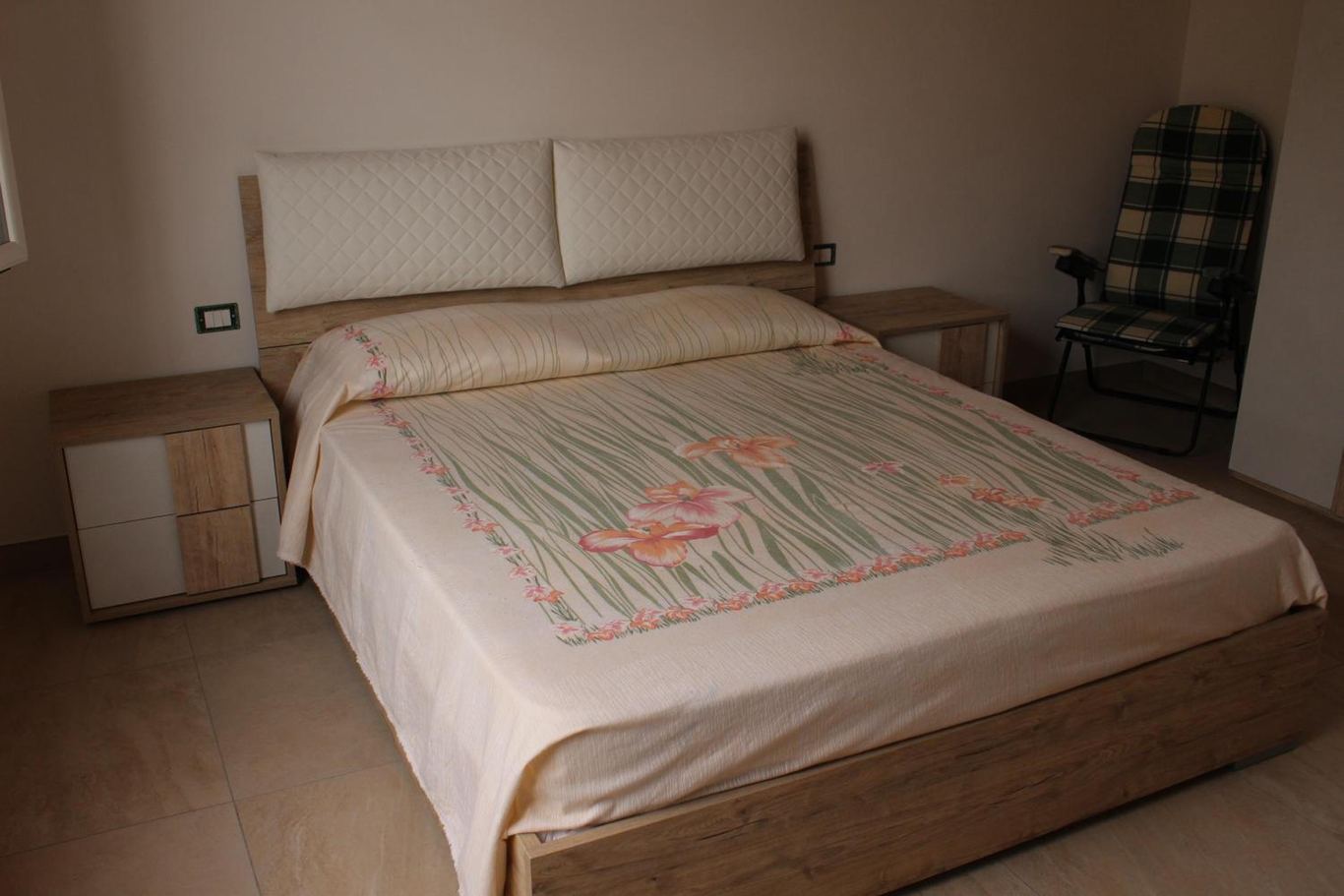 La camera matrimoniale con il letto, i comodini e la poltrona.