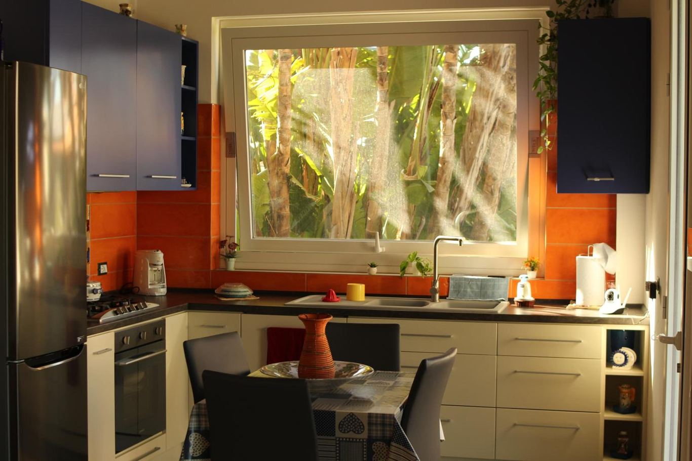 La cucina attrezzata con la finestra sulle palme e il tavolo per la colazione.