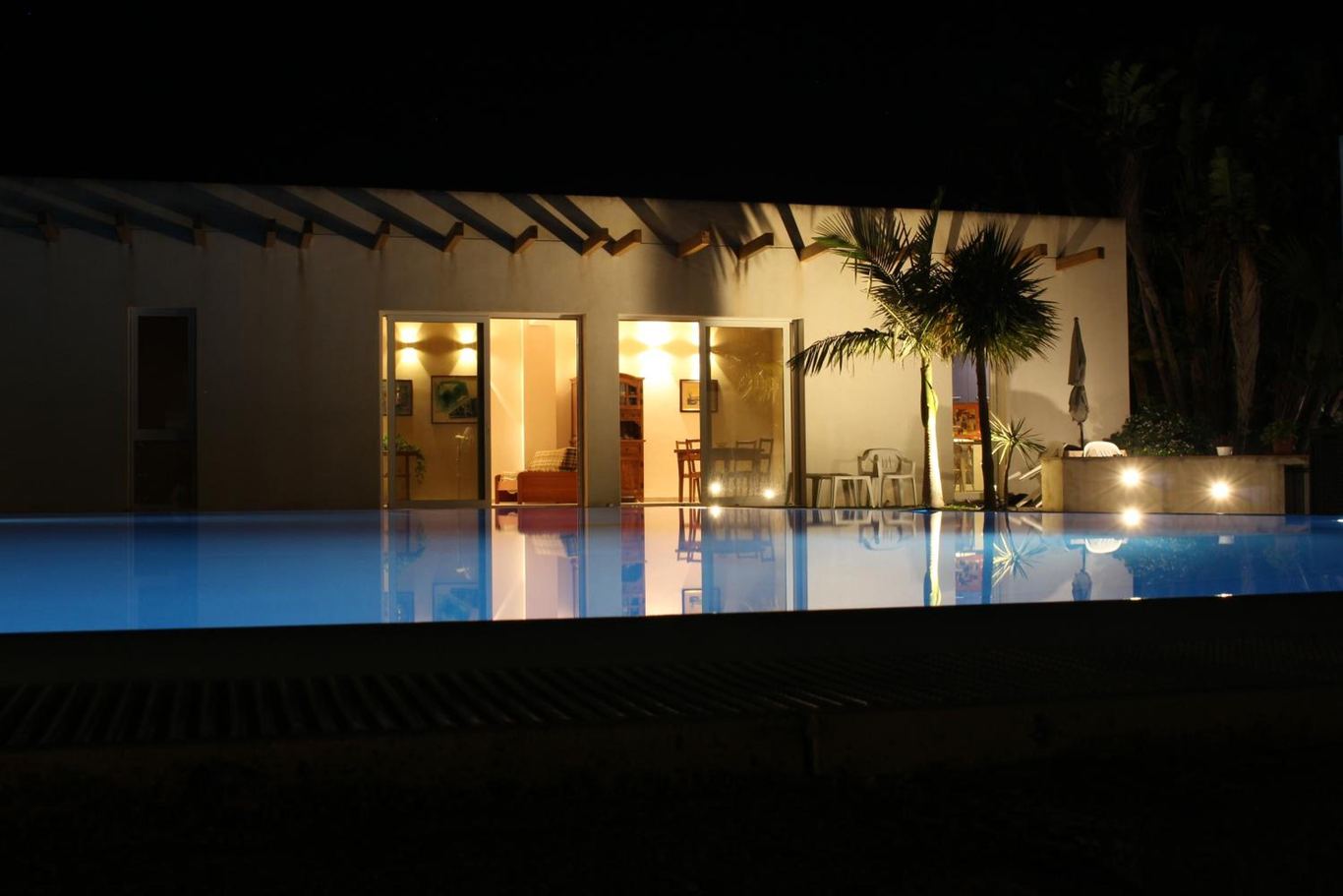 La villetta di notte, con le luci del living e la piscina illuminata.