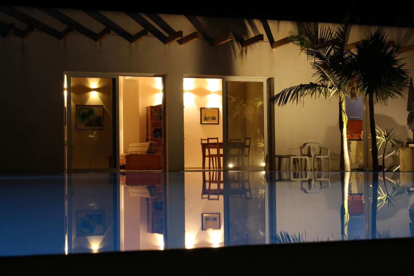 La villetta illuminata di sera, con le vetrate accese riflesse nella piscina.