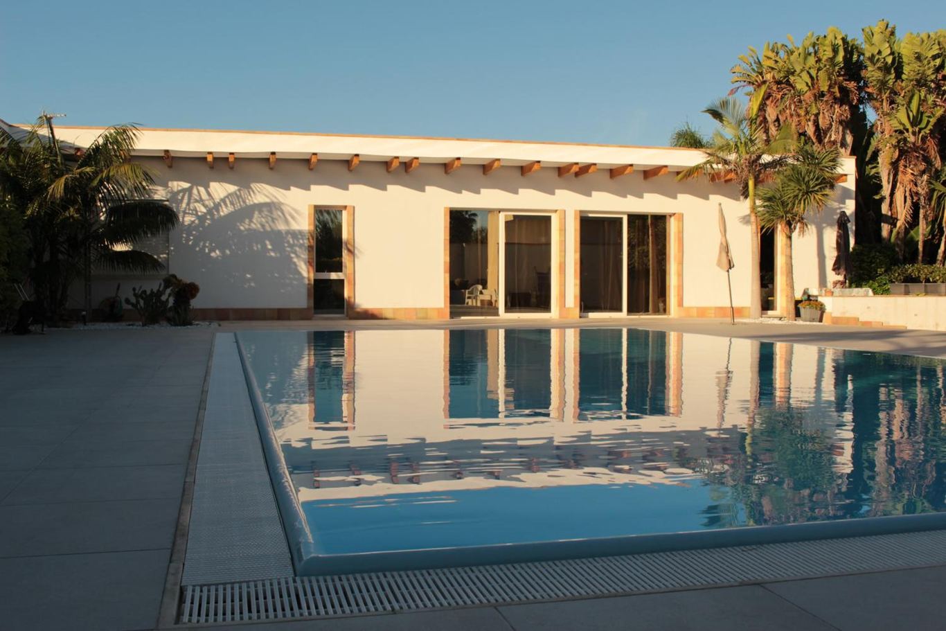 La villetta e le sue vetrate riflesse nell'acqua ferma della piscina.