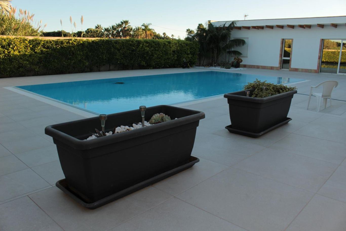 Due fioriere con le piante grasse sul bordo del solarium, accanto alla piscina.
